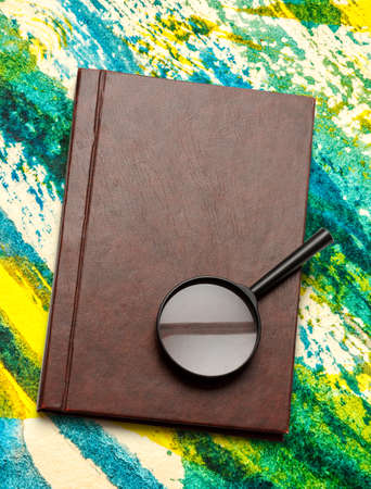 Notepad and magnifying glass on colorful backgroundの写真素材