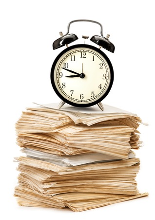 Stack of old paper documents and alarm clockの写真素材