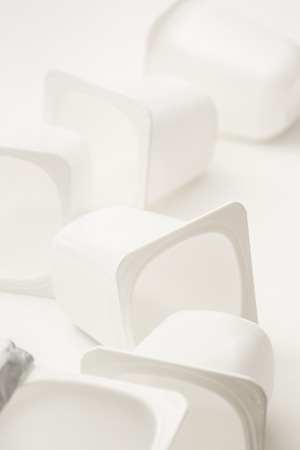 Empty crushed plastic yogurt pots on white