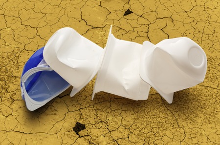 Empty crushed plastic yogurt pots on cracked backgroundの写真素材