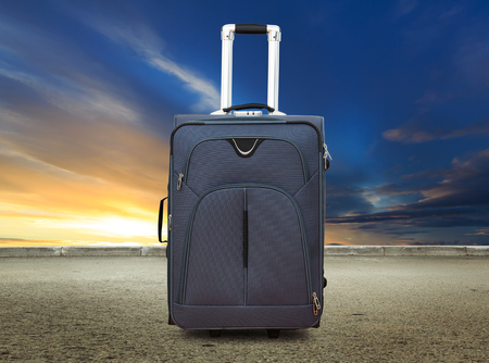 Suitcase at sunset sky and road backgroundの写真素材