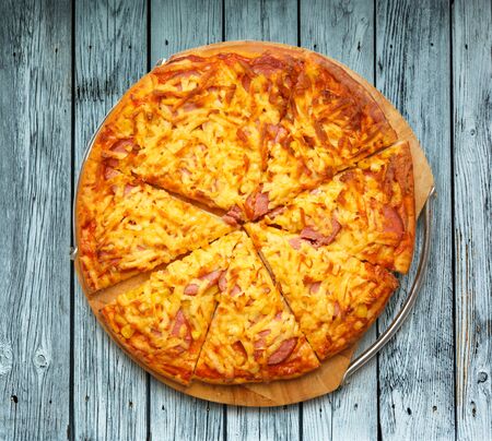 Sliced home pizza with cheese on wooden boardの写真素材