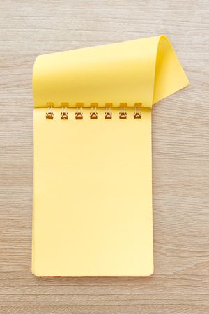 Blank yellow notepad on the wooden backgroundの写真素材