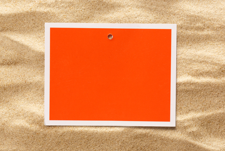 Blank red card on the sand backgroundの写真素材