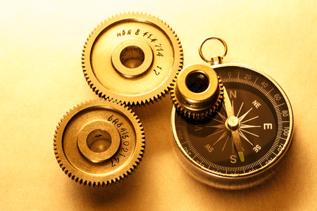 Three steel cogwheels with compass in closeupの写真素材