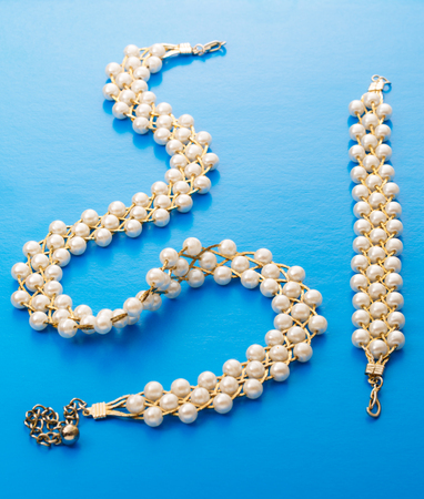Necklace and wristband with golden chain and white beadsの写真素材