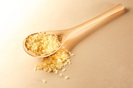 Heap of rice with wooden spoon in closeupの写真素材