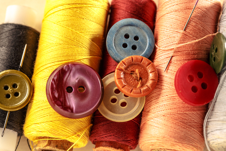 Thread bobbins, buttons and needles on paper backgroundの写真素材