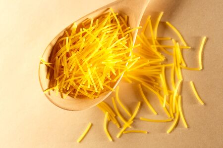 Short pasta tubes and wooden spoon closeupの写真素材