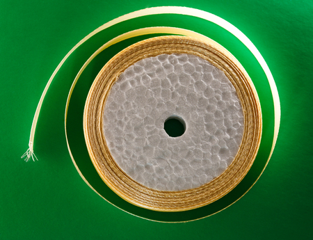 Cream ribbon in roll on green backgroundの写真素材