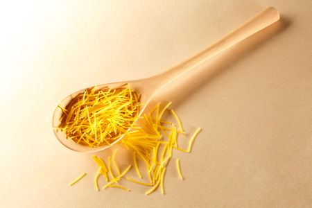 Short pasta tubes and wooden spoon closeupの写真素材