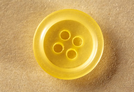 One yellow button on paper in closeupの写真素材