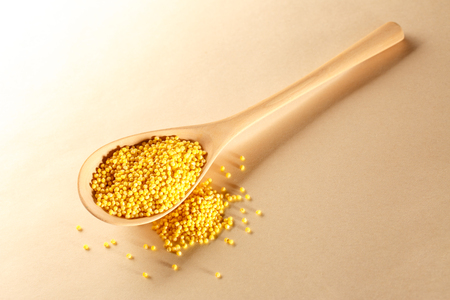Millet groats with wooden spoon on paperの写真素材