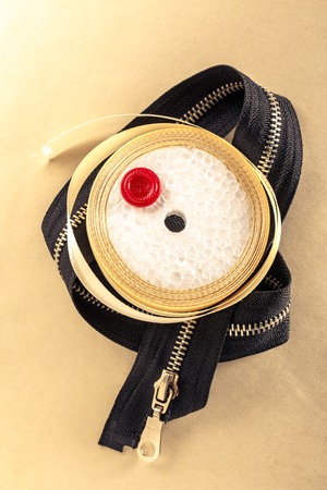 Red button, zipper and ribbon roll in closeupの写真素材