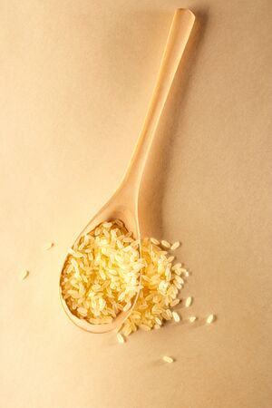 Heap of rice with wooden spoon in closeupの写真素材