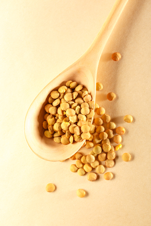 Raw lentil in wooden spoon on paper backgroundの写真素材