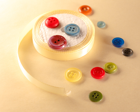 Colourful buttons and ribbon roll in closeupの写真素材