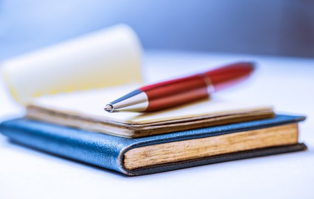 Notebooks with red pen in closeup as backgroundの写真素材