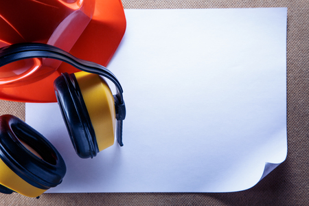 Red helmet, yellow earphones and blank sheet of paperの写真素材