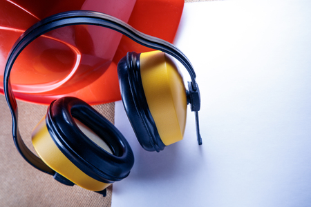 Red helmet, yellow earphones and blank sheet of paperの写真素材