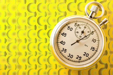 Stopwatch on yellow background in closeupの写真素材