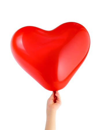 Red heart shaped balloon in child's handの写真素材