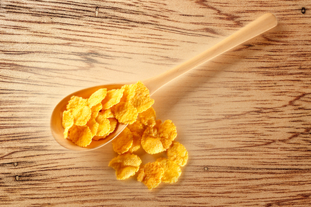 Wooden spoon with corn flakes on paperの写真素材