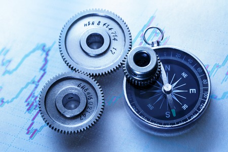 Three steel cogwheels with compass in closeupの写真素材