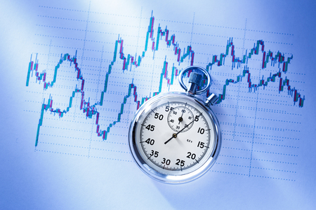 Candle stick graph chart of stock market investment trading with a clockの写真素材