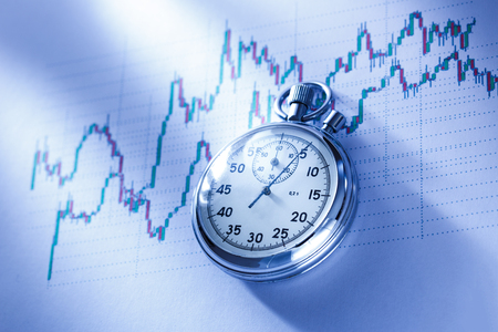 Candle stick graph chart of stock market investment trading with a clockの写真素材