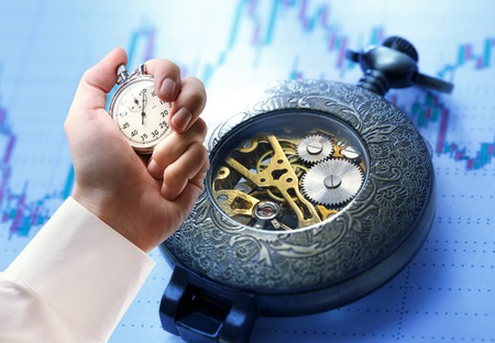 Candlestick chart graphic, watch and stopwatch in male handの写真素材