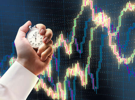 Candlestick chart graphic and stopwatch in male hand