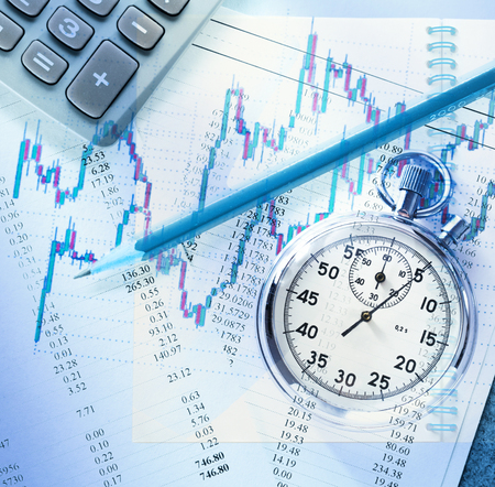 Candlestick graph chart, pencil and stopwatch in toningの写真素材