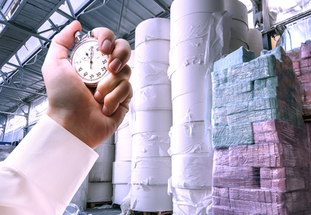 Paper products storehouse and stopwatch in male handの写真素材