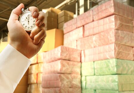 Paper products storehouse and stopwatch in male handの写真素材