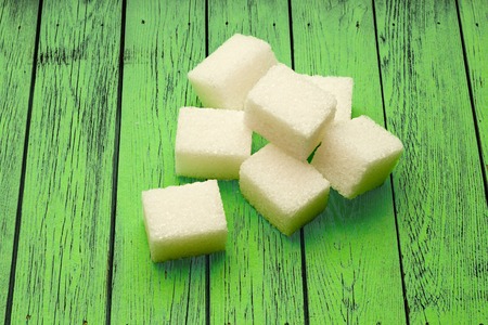 Sugar cubes on the green wooden backgroundの写真素材