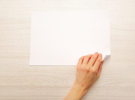 Woman's hand turning over sheet of paperの写真素材