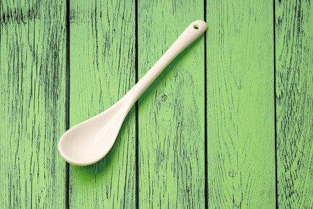 Ceramic spoon placed on green wooden backgroundの写真素材