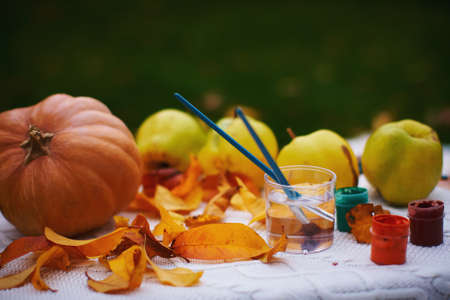 Autumn still life with pumpkin and apples, paints and brushes on a table.の写真素材