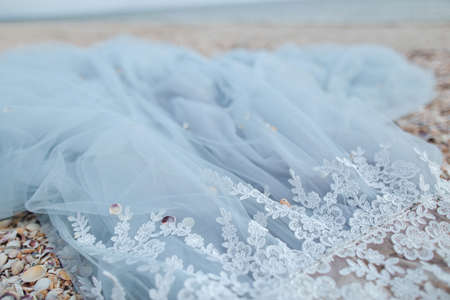 Blue background with fabric and lace on the beach. A fragment of the wedding dressの写真素材