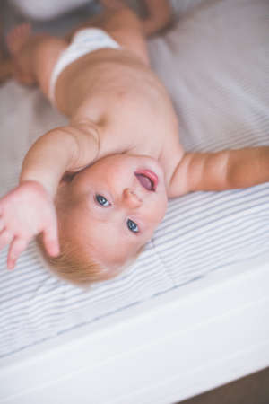 Child on a bed smiles and stretches a hand to the chamber. The effect of film photographyの写真素材