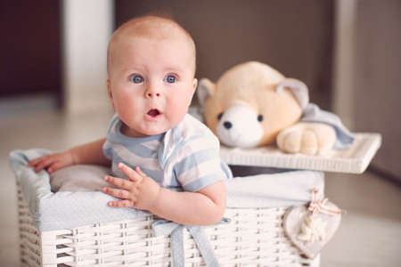 Little surprised baby in white wicker basketの写真素材