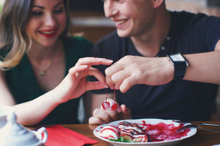 Guy and a girl share the cherries taken from the cakeの写真素材