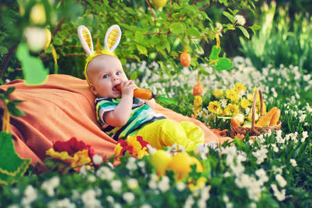 Baby in the Bunny suit bites a carrot. Easter decorの写真素材