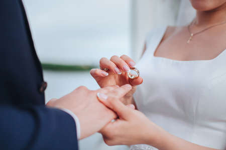 Bride is putting a wedding ring to the groom. Hand closeupの写真素材