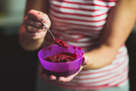 Jam in a bowl in female hands with a spoonの写真素材