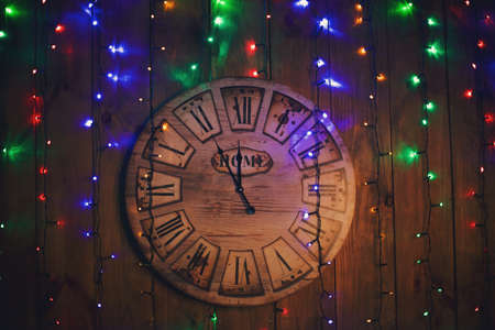 Wooden hours on a wooden wall show five minutes about new year.の写真素材