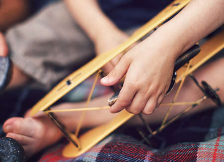 Child's hand holding toy yellow plane, closeupの写真素材