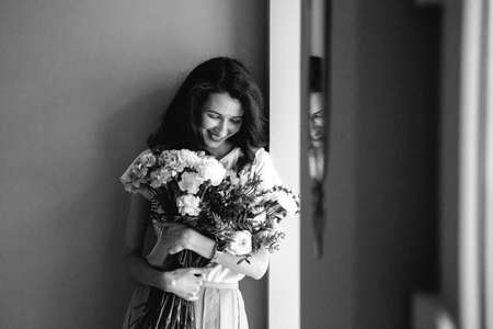 smiling young beautiful girl black and white portrait with the bouquet of flowersの写真素材