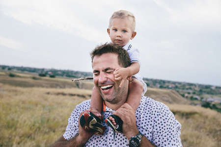 adorable smiling toddler hugging his father and holding his neck